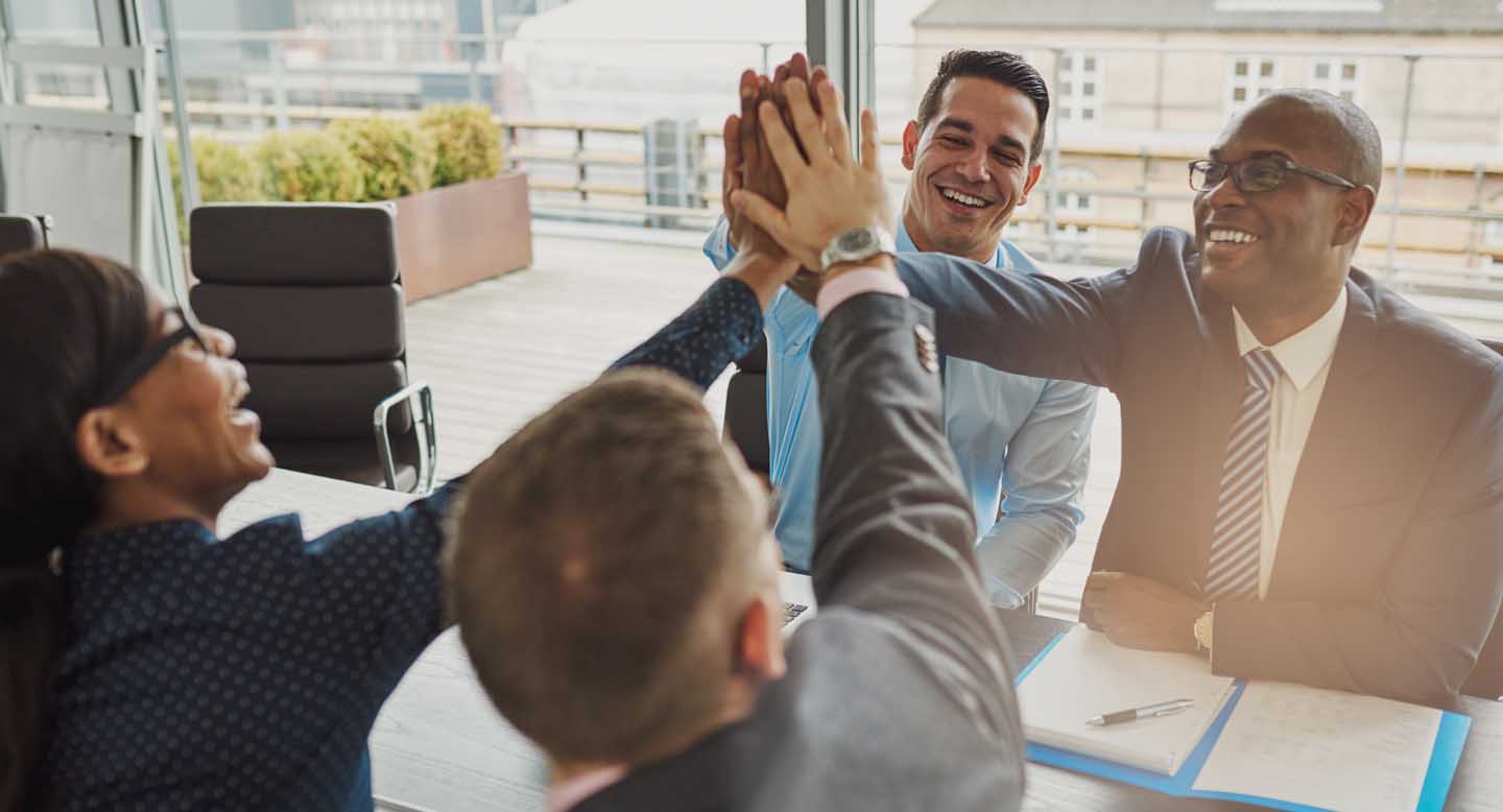 employees around a conference table giving high fives