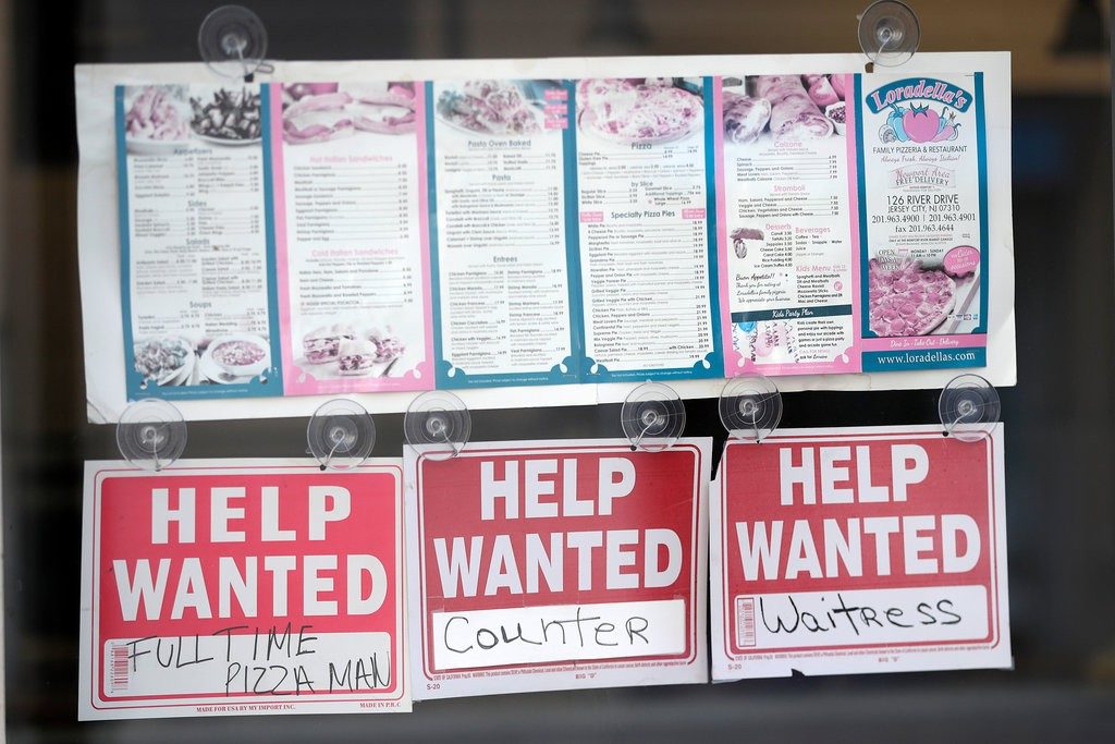 help wanted signs in window underneath a shop's menu