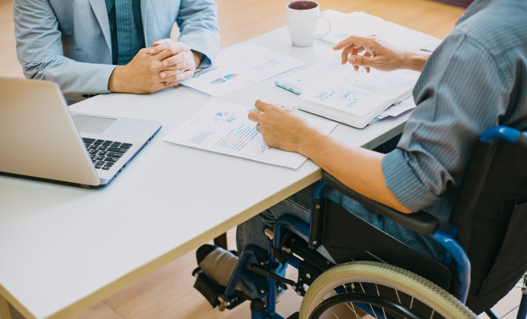 injured employee in a wheelchair going over documents with a coworker