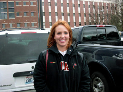 A redheaded woman dressed in a black hoodie smiles in a family photo of Sunny Taylor