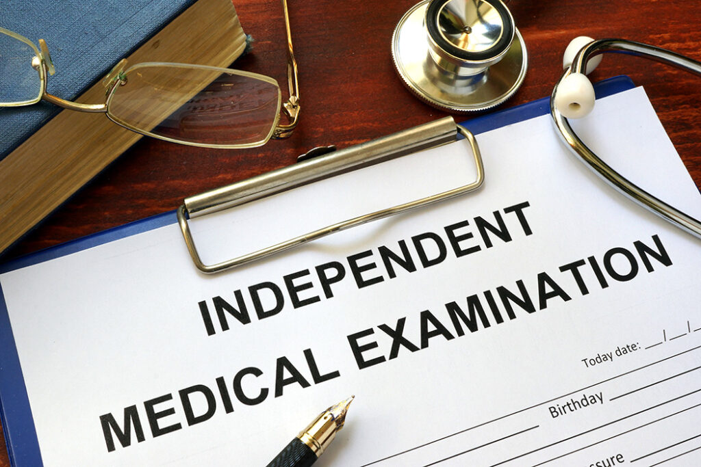 Independent Medical Examination (IME) form on a wooden table.