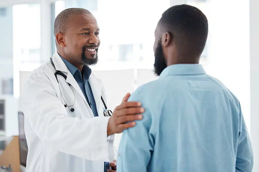 A doctors reassures his patient with a hand on the shoulder.