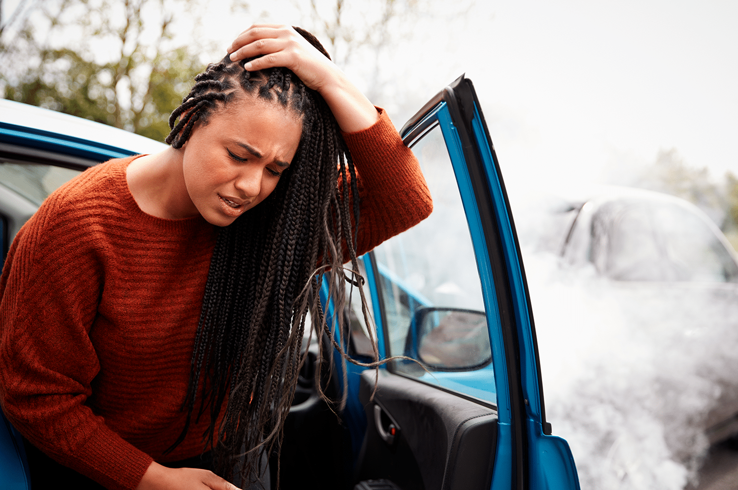 Female motorist with head injury getting out of a car after a crash