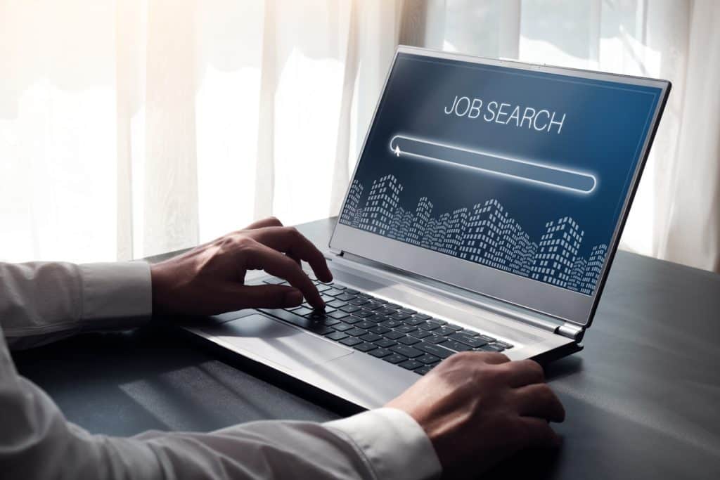 Person's hands typing on laptop keyboard while job searching Washington jobs