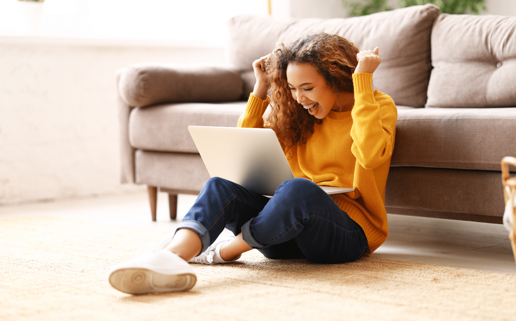 young woman with laptop celebrating winning a scholarship