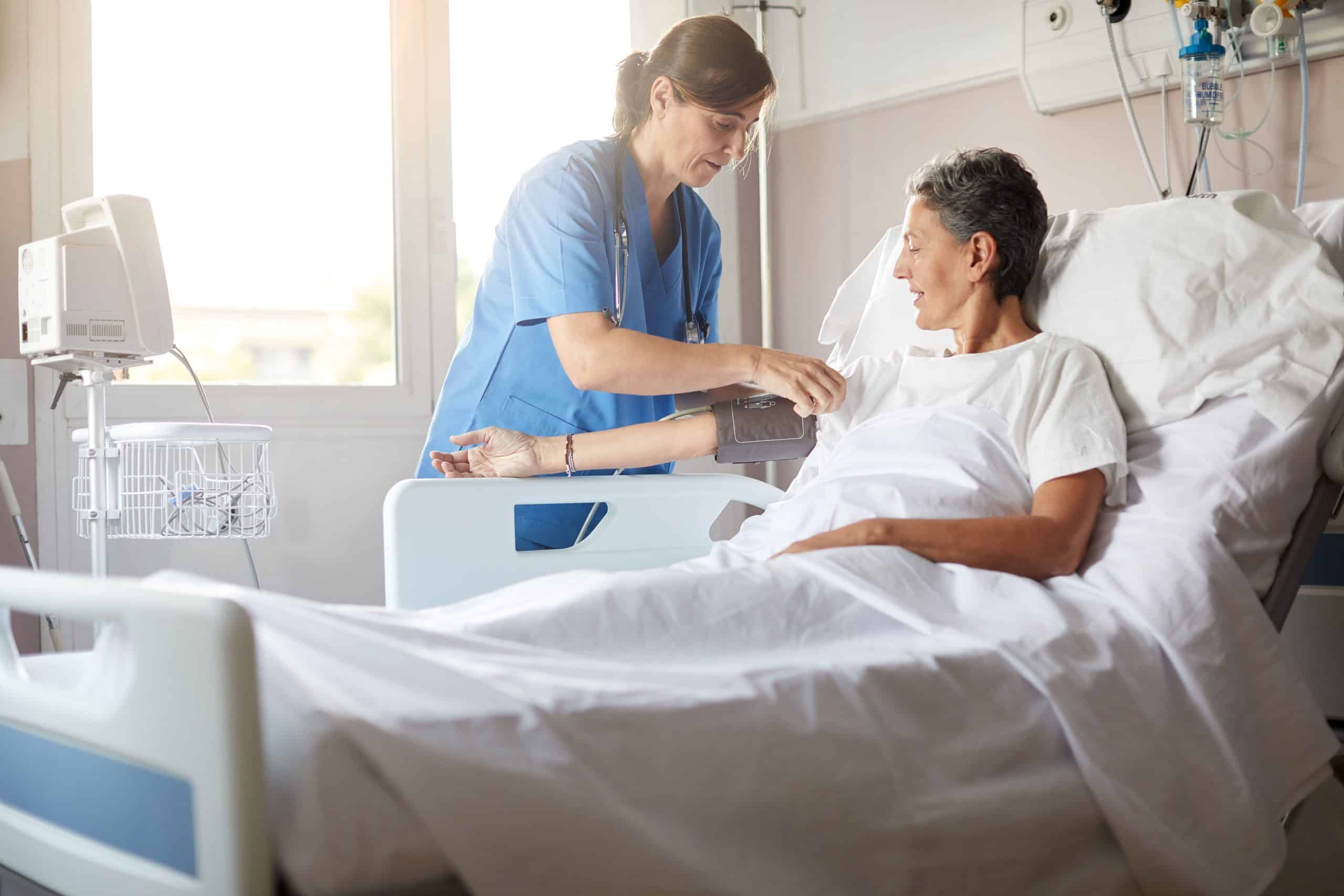 ATTACHMENT DETAILS female-nurse-leaning-over-bedside-while-attaching-the-blood-pressure-armband-to-a-female-patients-rightarm