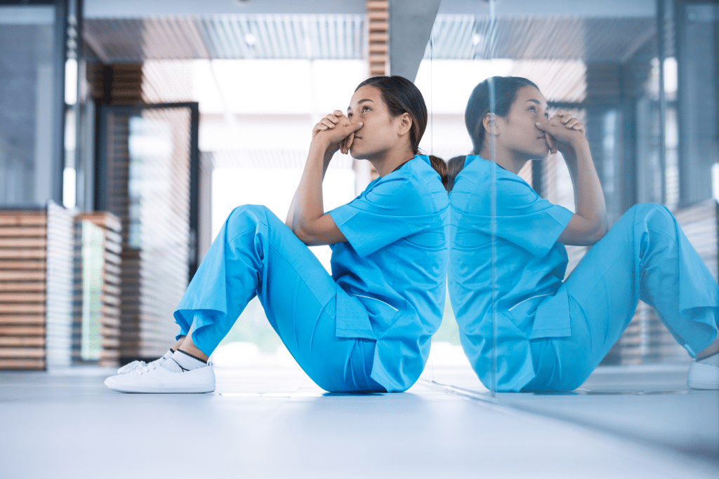 nurse sitting on the ground with a worried expression on her face