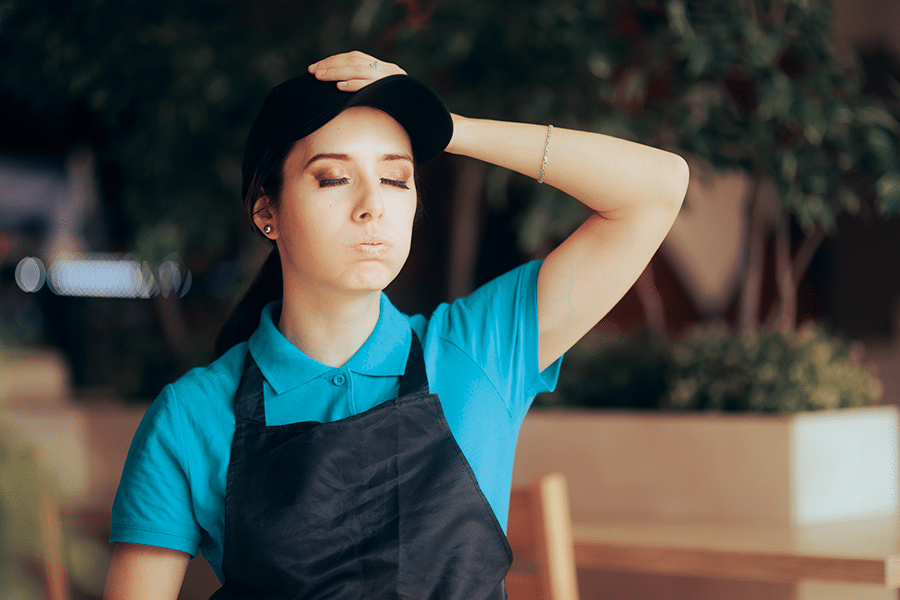 tired employee wearing a black apron and teal tshirt