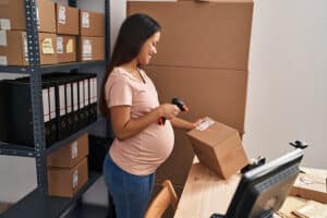 Pregnant worker scanning a box with a shipping label