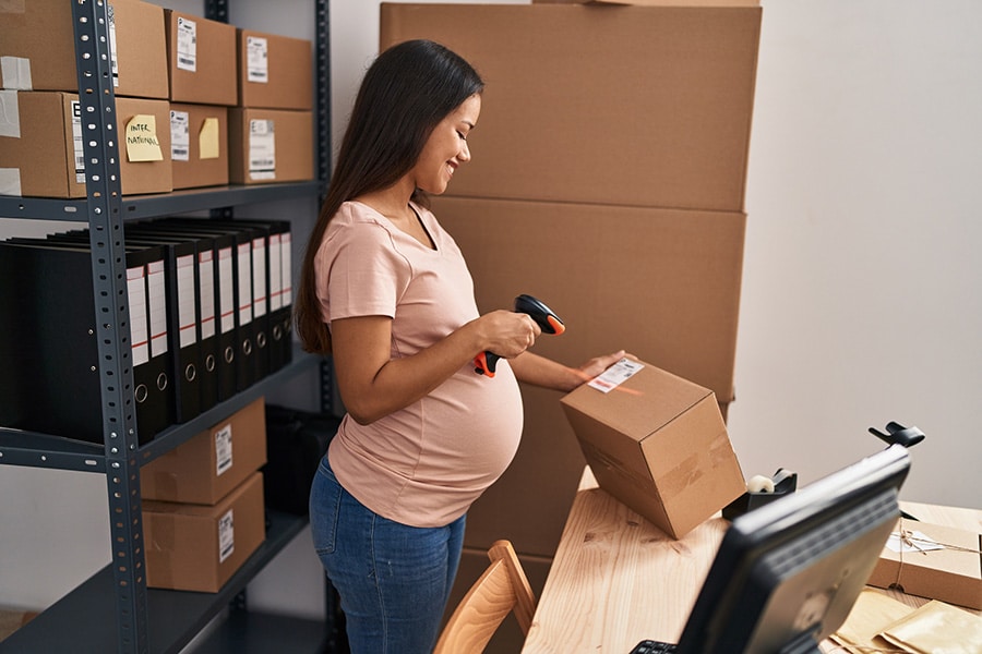 Pregnant worker scanning a box with a shipping label