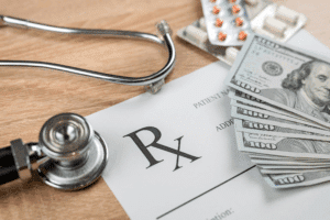 Prescription, stethoscope, medication, and one hundred dollar bills on a table