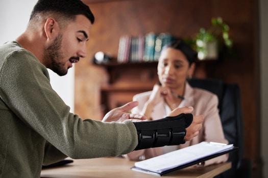 injured worker with wrist brace reviewing paperwork
