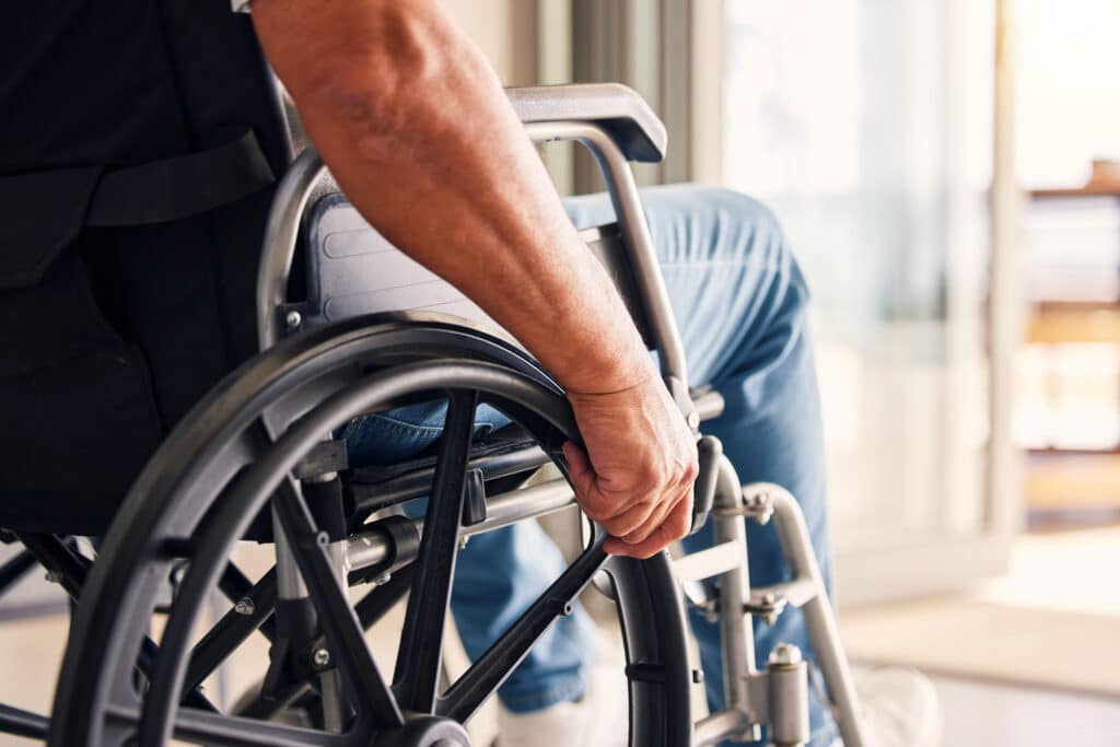 Man, hands and wheelchair for support, hope or travel in healthcare or medicare at home. Closeup of male or person with a disability moving on chair for mobility, surgery or wellness in the house
