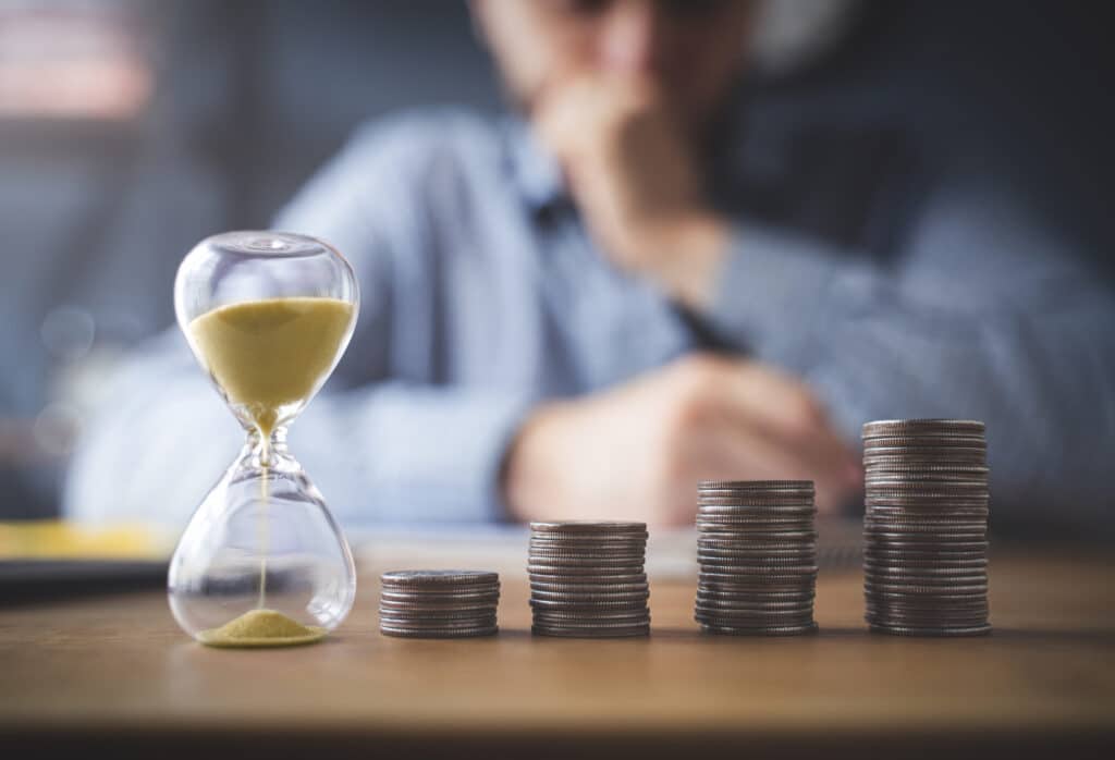 man watching hourglass and stacks of change