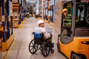 Big industry pallet warehouse with two people working using forklift and on of them in wheelchair