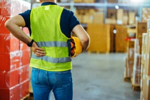 A man experiencing back pain at working in a warehouse