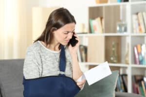 Sad disabled woman claiming on mobile phone about paper notice at home