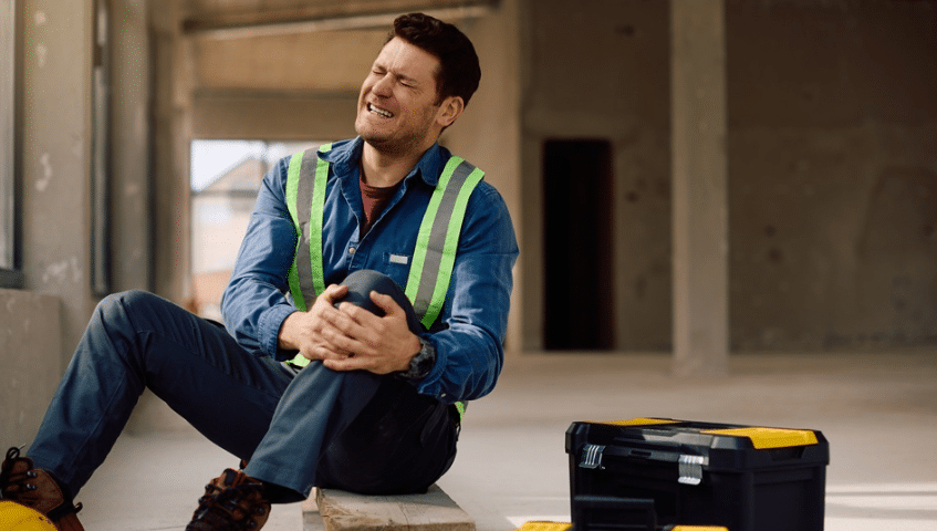 An injured construction worker sitting on the ground