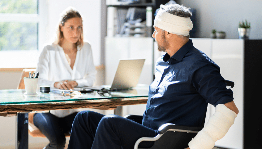 Injured man in a wheelchair speaking with a woman at a desk